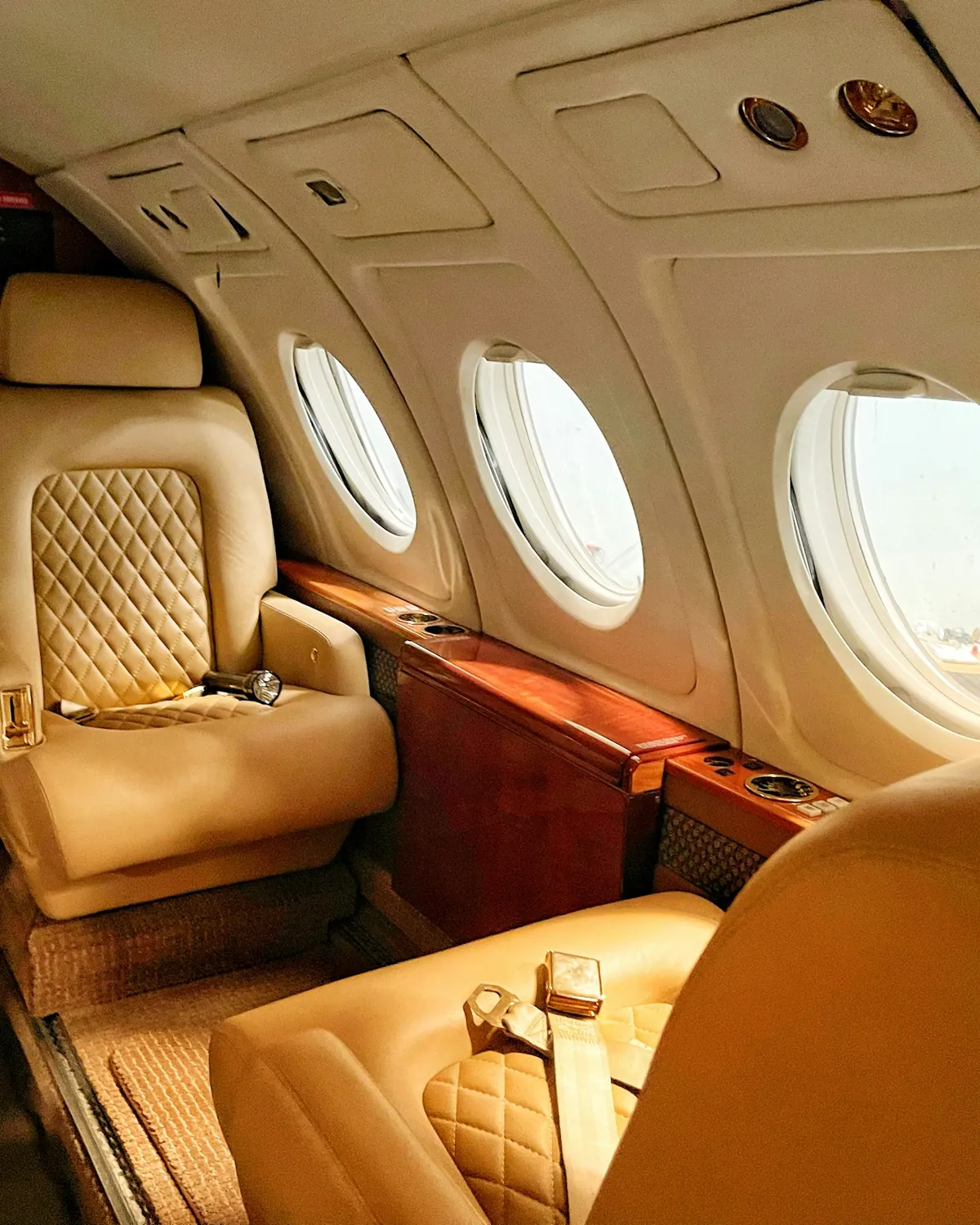 Quilted cream leather club seat beside oval windows in a compact cabin